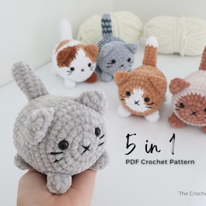 May include: A collection of five crocheted cat toys in various colors, including gray, brown, and orange, with white accents. Each cat has a unique pattern and facial expression. The image also includes the text "5 in 1 PDF Crochet Pattern".