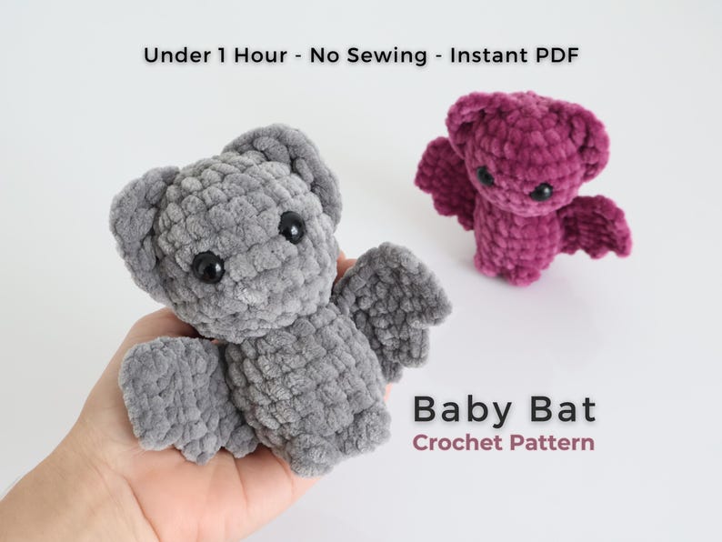 K&ouml;nnte beinhalten: Zwei geh&auml;kelte Babyflederm&auml;use, eine graue und eine lila, mit schwarzen Augen und Fl&uuml;geldarstellungen. Die graue Fledermaus wird in einer Hand gehalten. Der Text lautet "Under 1 Hour - No Sewing - Instant PDF" und "Baby Bat Crochet Pattern."