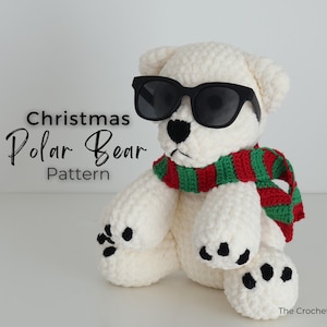 May include: A crocheted polar bear wearing black sunglasses and a red and green striped scarf. The bear has black paw pads and a black nose. Text on the image reads "Christmas Polar Bear Pattern".