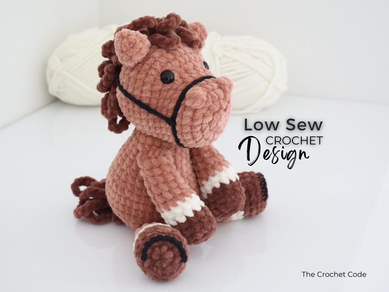 A handmade, plush crochet horse in shades of brown, with white accents on its legs. The horse has a black bridle and dark brown mane and tail. The text "Low Sew Crochet Design" is displayed on the right side of the image.