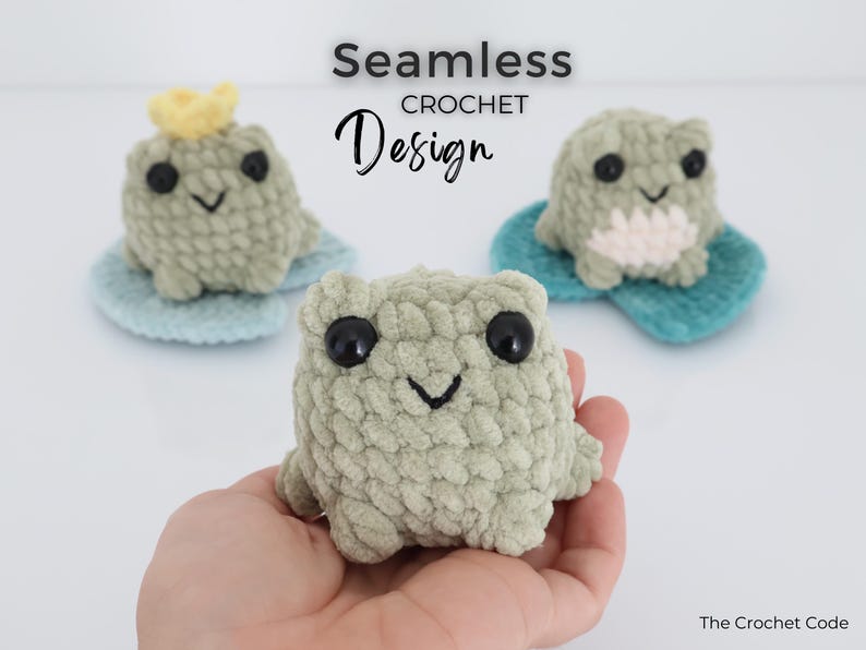 May include: Three handmade crochet frog toys in shades of green, each with large black eyes and a smiling mouth. One frog wears a yellow crown. The frogs sit on blue lily pads. The text "Seamless Crochet Design" is above the frogs.