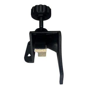 May include: A black clamp with a textured knob and a padded contact surface. The clamp has a lever arm and a rectangular body. The knob is ribbed for grip.
