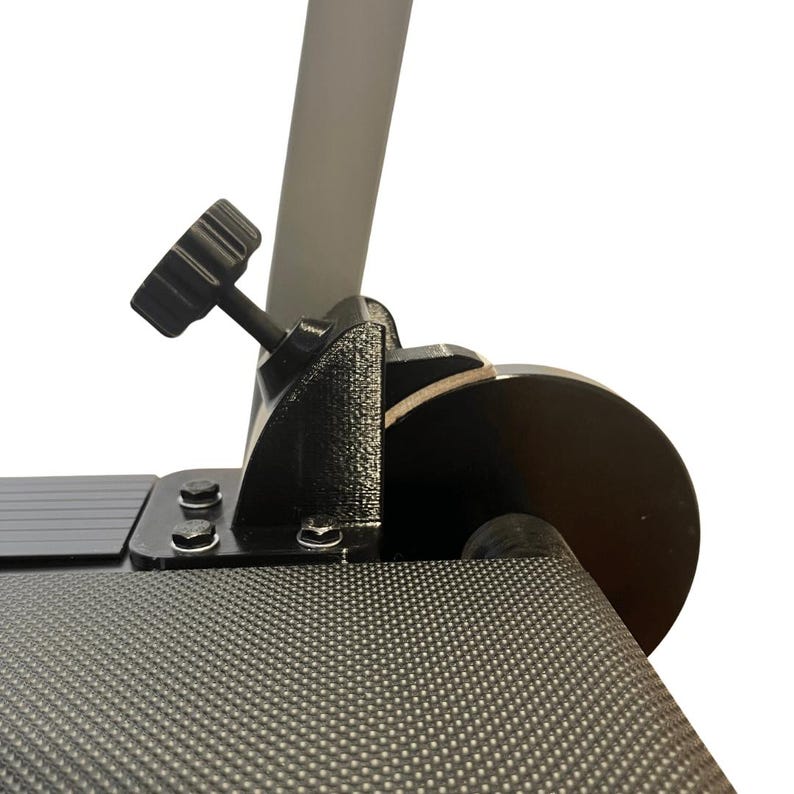 May include: Close-up of a black adjustable clamp with a textured surface. The clamp features a black knob and is attached to a gray pole and a black, circular component. The background is white.