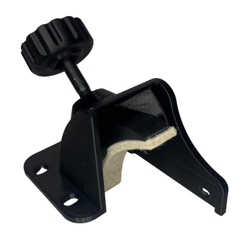 May include: Black adjustable clamp with a textured knob and a felt-lined grip. The clamp has a mounting plate with two holes and a curved arm. The clamp is designed to hold an object in place.