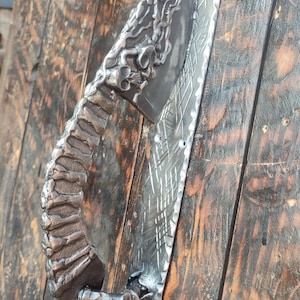 Door iron pull. The foot handle of a door. A grim steel pull. Door decoration. Skulls on a knife. Halloween.