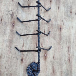 Peut inclure: Un porte-manteau mural en métal noir avec plusieurs crochets pour suspendre des objets. Le porte-manteau présente des motifs floraux décoratifs et un support central torsadé, idéal pour les bijoux.