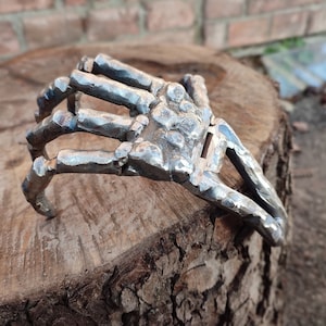 Metal holder in the form of a skeleton of a human hand. Gothic handmade home decor. Sculpture
