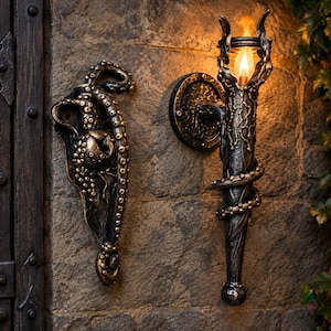 May include: A dark metallic wall-mounted torch light featuring an octopus tentacle design wrapped around the shaft, paired with a matching vertical door handle shaped like an octopus with textured suckers, both mounted on a stone wall.