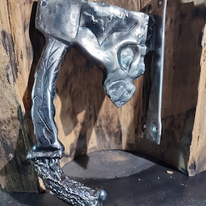 May include: A silver metal door handle with a unique, organic design. The handle is shaped like a skull with a textured, tree-like base.