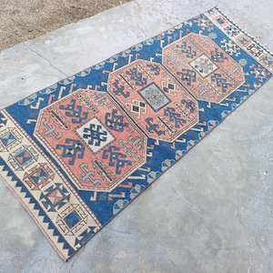 May include: A white ceramic mug with a black handle and the text "But First, Coffee" in a bold, black font. The mug is set against a blurred background, suggesting a cozy setting.