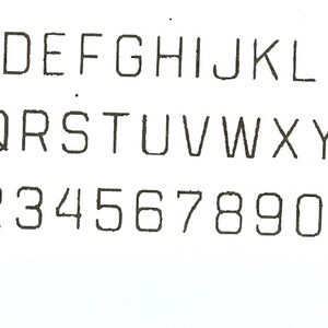 May include: A black and white image of the alphabet in uppercase letters, followed by the numbers 1 through 9 and 0.