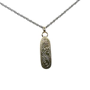 May include: A gold-colored pendant necklace with an oval-shaped pendant. The pendant features an engraved floral design and hangs from a delicate silver chain. The necklace is displayed against a white background.