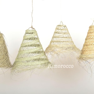 May include: Four woven lampshades in various shades of beige and cream. The lampshades are cone-shaped and have a fringe around the bottom.