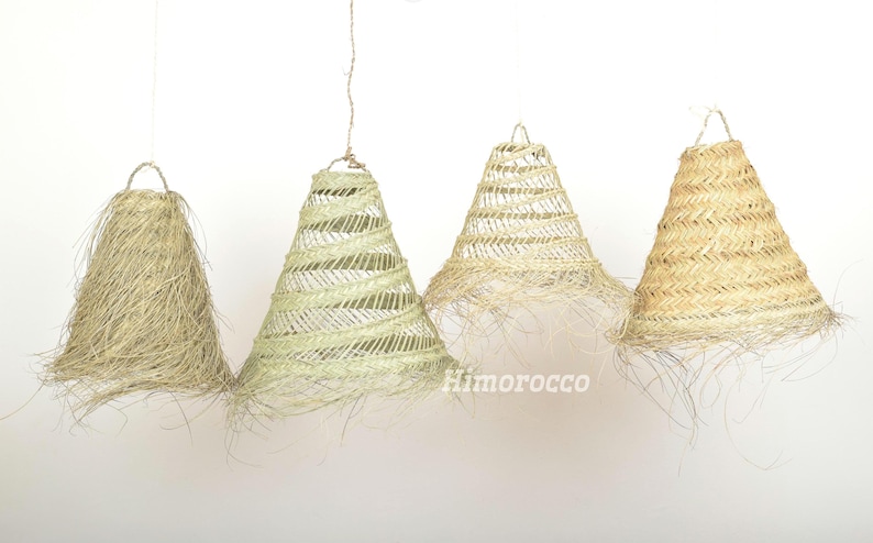 May include: Four woven lampshades in various shades of beige and cream. The lampshades are cone-shaped and have a fringe around the bottom.