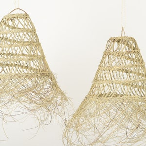 May include: Two natural woven pendant light shades with a fringe detail. The shades are made of natural materials and have a rustic, bohemian style.