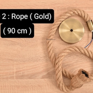 K&ouml;nnte beinhalten: Dekorative Pendelleuchte aus Seil mit goldfarbener Hardware. Das Seil hat eine nat&uuml;rliche beige Farbe, und die Leuchte enth&auml;lt eine Deckenplatte, ein Kabel und eine Montagehalterung. Der Text auf dem Bild lautet "Style 2: Rope (Gold) (90 cm)".