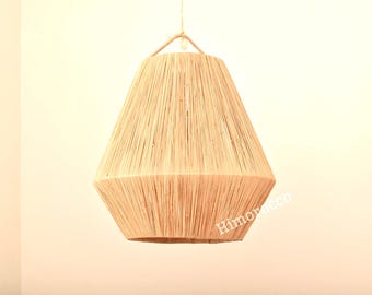 May include: A beige, geometric pendant light fixture. The lampshade is made of woven natural fibers, with a tapered shape and a textured surface. The light hangs from a rope and is suitable for interior lighting.