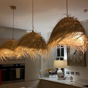 May include: Three woven pendant lights hang from the ceiling in a kitchen. The lights are made of natural materials and have a warm, inviting glow.
