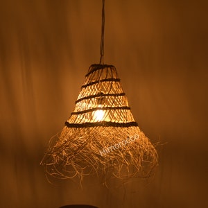 May include: A woven pendant light fixture with a natural, straw-like material. The light is on and casting a warm glow.