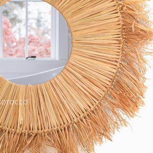 Pu&ograve; includere: Specchio da parete rotondo con cornice in paglia naturale intrecciata. Lo specchio ha un centro in vetro circolare e un design a raggiera. La cornice &egrave; di colore marrone chiaro, con un bordo a frange. Un elemento decorativo per la casa.