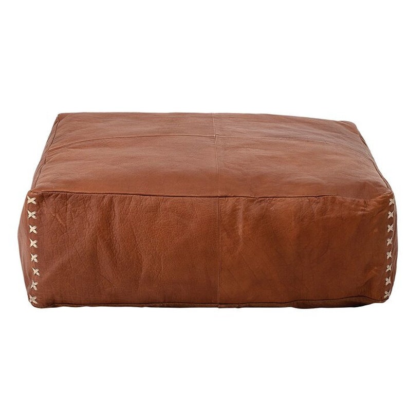 May include: A brown leather ottoman with white stitching around the edges. The ottoman is square and has a tufted top.