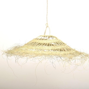 May include: A woven straw lampshade with a fringe of loose strands hanging from the bottom.