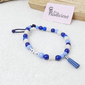 Könnte beinhalten: Ein blaues und weißes Perlenhalsband für Haustiere mit dem Namen "NALIA" auf den Perlen. Das Halsband hat einen blauen Quasten.