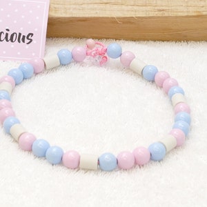 Op de afbeelding: Een lichtblauwe en roze kralenketting met witte kralen. De ketting heeft een klein roze bedeltje.