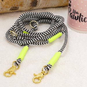 May include: A black and white chevron patterned dog leash with neon yellow accents and two gold clips.