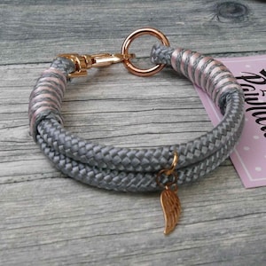 Könnte beinhalten: Ein graues und rosafarbenes Hundehalsband aus Seil mit einem roségoldenen D-Ring und einem kleinen roségoldenen Flügel-Anhänger.