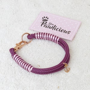 Op de afbeelding: Een maroon touwhalster met roze strepen en een gouden ankerbedel. Het halster heeft een gouden metalen sluiting. Het halster ligt op een witte achtergrond met een roze kaart waarop "Liba Pawlicious" staat.