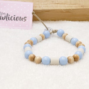Op de afbeelding: Een lichtblauwe en natuurlijke houten kralen armband. De armband is gemaakt met ronde houten kralen en lichtblauwe en witte ronde kralen.