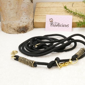 May include: Black rope dog leash with gold metal hardware and a spring-loaded clip. The leash is coiled and laid out on a white surface.