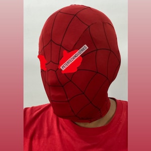 Op de afbeelding: Een rood en zwart spandex masker met een spinnenwebontwerp. Het masker heeft ooggaten en de tekst "PETERTECHINDUSTRIES" is op de voorkant gedrukt.