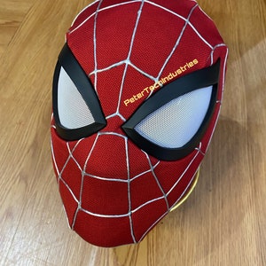 May include: Red and white Spider-Man mask with a black eye mask and a white mesh. The mask has the text "PeterTechIndustries" on the side.