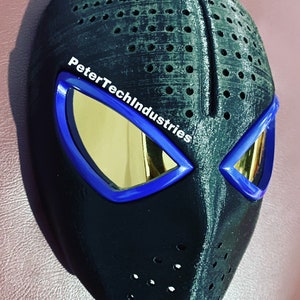 May include: Black 3D printed mask with blue and gold eye lenses. The mask has a textured surface with small holes and the text "PeterTechIndustries" is printed on the side.