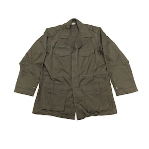 Può includere: Giacca verde oliva in stile militare con collo e quattro tasche anteriori. La giacca ha maniche lunghe con polsini abbottonati e spalline sulle spalle. Una piccola toppa è visibile sul petto.