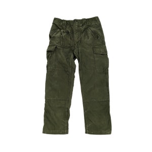 May include: Olive green cargo pants with multiple pockets on the legs and front. The pants have a button and zipper closure and are made of a durable fabric. The pants are designed for utility and outdoor wear.