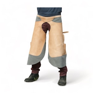 Könnte beinhalten: Eine braune Leder-Arbeits-Schürze mit einem blauen Canvas-Latz und Taschen. Die Schürze hat eine große Öffnung im Rücken für einfache Bewegung.