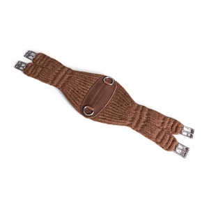 Puede incluir: Una cincha de caballo de punto marrón con detalles de cuero y hebillas metálicas.