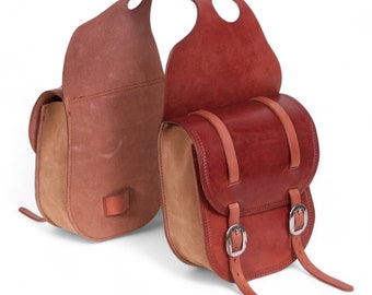 May include: A pair of brown leather saddlebags with buckles and straps. The bags are made from a combination of brown and tan leather.