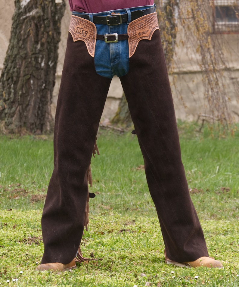 Pu&ograve; includere: Chaps in pelle marrone con frange e una cintura con fibbia. I chaps hanno un design decorativo sul davanti con le iniziali "MV".