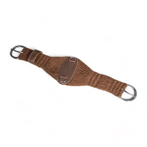 Puede incluir: Cincha de punto marrón con detalles de cuero y hebillas plateadas. La cincha está diseñada para usarse con una silla de montar.