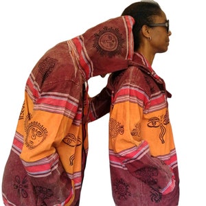 May include: Two hooded jackets with a colourful striped pattern and black and orange sun and eye designs. The jackets have a drawstring at the bottom.