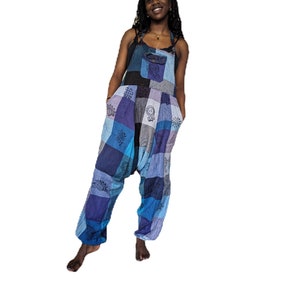 May include: A pair of blue and purple patchwork dungarees with a loose, baggy fit. The dungarees have a variety of floral and geometric patterns.