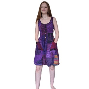 May include: A purple patchwork dress with a button-up front and pockets. The dress is made of a soft, flowing fabric and has a relaxed fit.
