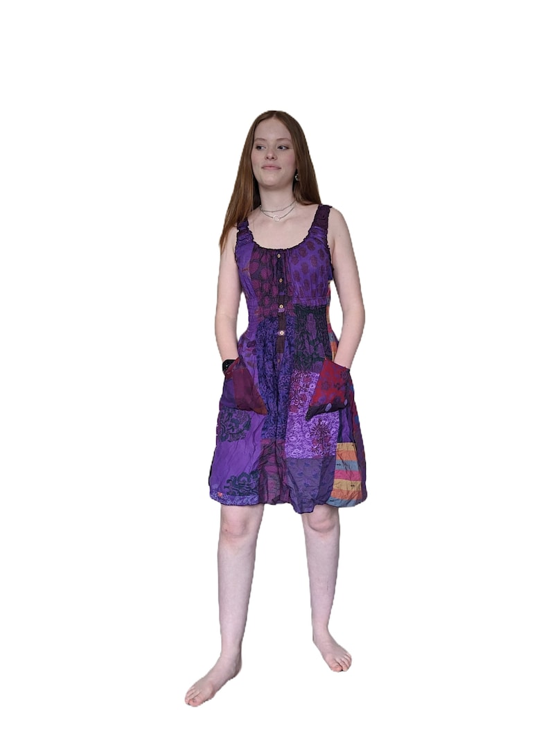 May include: A purple patchwork dress with a button-up front and pockets. The dress is made of a soft, flowing fabric and has a relaxed fit.