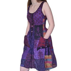 May include: A purple patchwork dress with a scoop neck and a button closure. The dress has a fitted bodice and a flowy skirt with pockets.