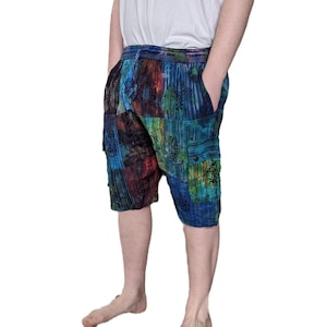 May include: A pair of multi-coloured patchwork shorts with a drawstring waist and multiple pockets. The shorts have a blue, green, red, and black colour scheme with a floral pattern.