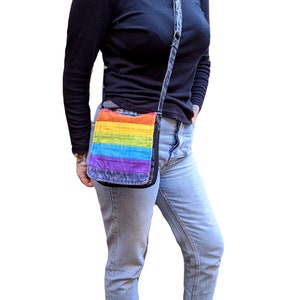 Sac à bandoulière pliable en coton arc-en-ciel Fairtrade en coton délavé en 4 couleurs avec bandoulière réglable, 2 poches intérieures et une poche zippée à l'extérieur.